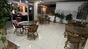 A patio area with wicker furniture, potted plants, and a view of the interior. - Özgür Family Otel (Antalya)