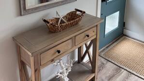 Ein Holzkonsolentisch mit einem gewebten Korb, einer klaren Acryl-Koralle und einer blauen Tür mit geätzten Glasscheiben.