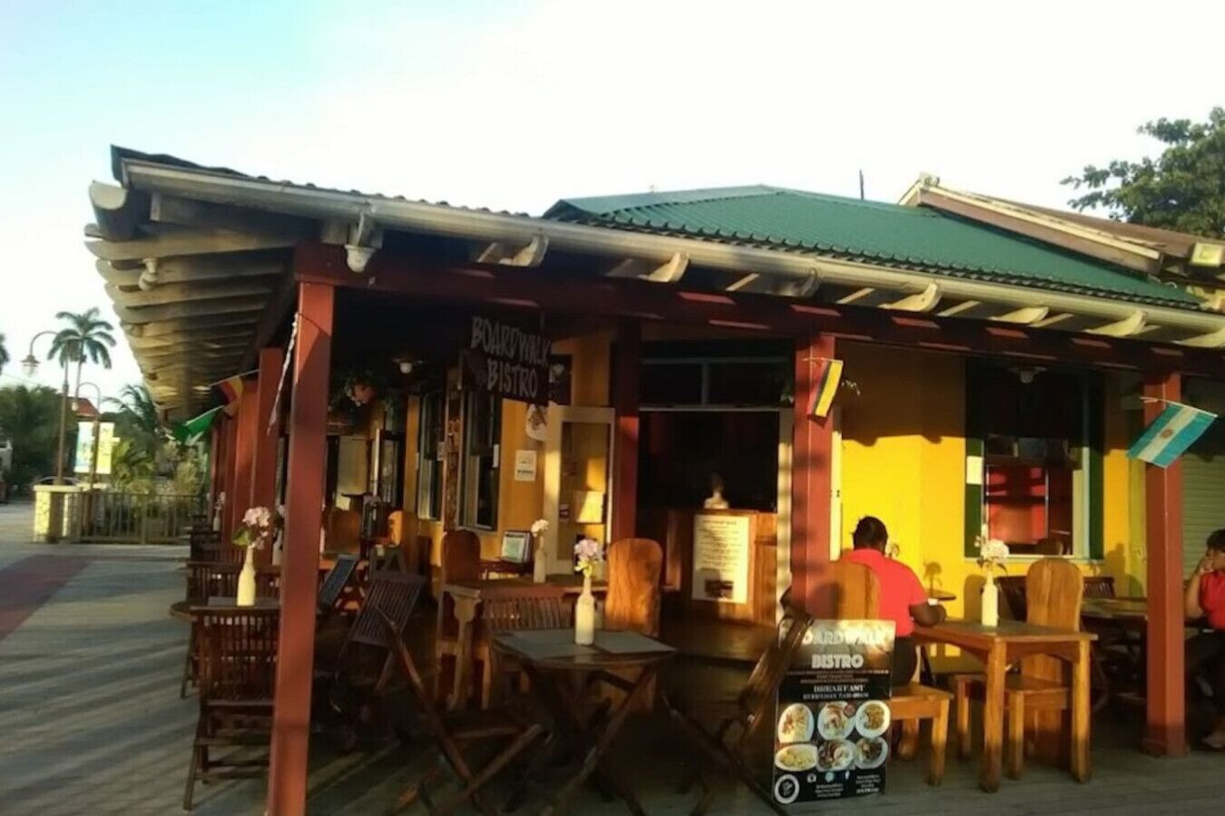 A restaurant with outdoor seating, a signboard, and a menu display.