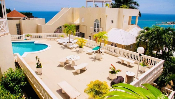A rooftop pool area with lounge chairs, a small pool, and a view of the ocean.