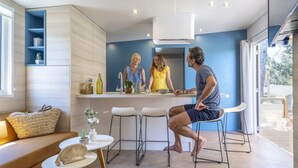 A modern kitchen with a central island, bar stools, and a seating area with a sofa and a small table. - ZEcamping 3* 200m plage locatif TV LV clim 40m2 6 pers (Hyères)
