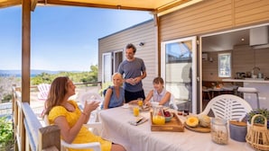 A family dining outdoors on a patio with a view of the landscape. - ZEcamping 3* 200m plage locatif TV LV clim 40m2 6 pers (Hyères)