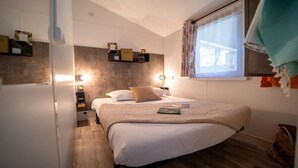 Ein Schlafzimmer mit Bett, Nachttischlampen, einem Fenster mit Vorhängen und einem Regal mit Gegenständen.