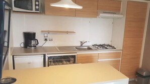 A compact kitchen with a microwave, coffee maker, sink, stove, and a small oven. - Camping 4 étoiles - Parc aquatique - ccbahgb (Saint-Cyprien)