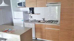 A compact kitchen with a microwave, coffee maker, sink, and gas stove. - Camping 4 étoiles - Parc aquatique - ccbahgb (Saint-Cyprien)
