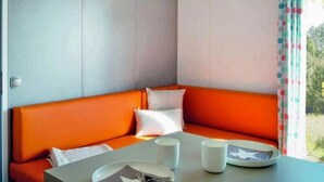 A room with a corner sofa, a small table with a plate, a cup, and a fork. - Camping 4 étoiles - Parc aquatique - ccbahgb (Saint-Cyprien)