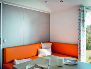 Ein Zimmer mit einer Eckcouch, einem kleinen Tisch mit Teller, Tasse und Gabel.