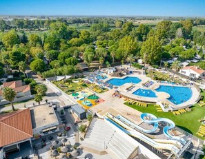 Ein Resort mit mehreren Schwimmpools, einer Wasserrutsche und Blick auf die umliegende Grünfläche.