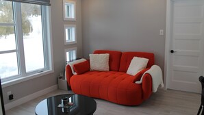 Una habitación con un sofá rojo, una mesita redonda y una puerta blanca.