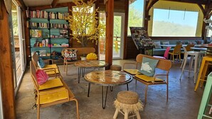 Ein gemütlicher Leseplatz mit Bücherregalen, Korbmöbeln und einem großen Fenster.