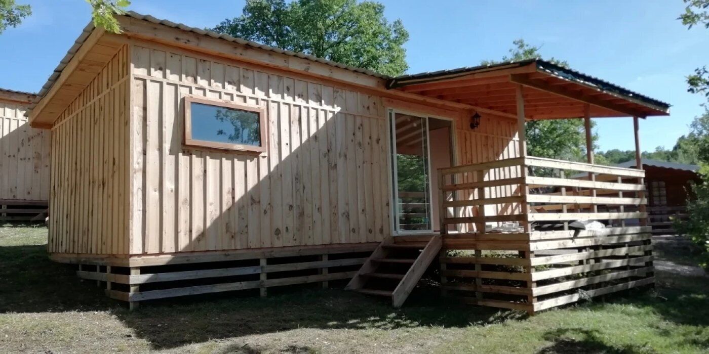 Een houten hut met een veranda en een raam.