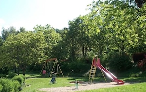 En legeplads med gynger og rutschebane i en park.