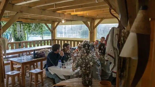 An outdoor wooden deck with tables and chairs, a wooden ceiling, and a view of greenery outside. - ZEcamping 3* piscine locatif 59m2 4 pers (Montaut)