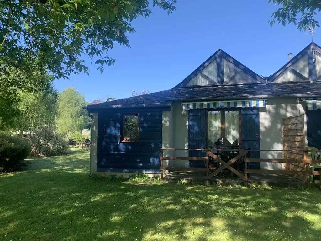 A rustic building with a blue exterior, a wooden fence, and a small porch.