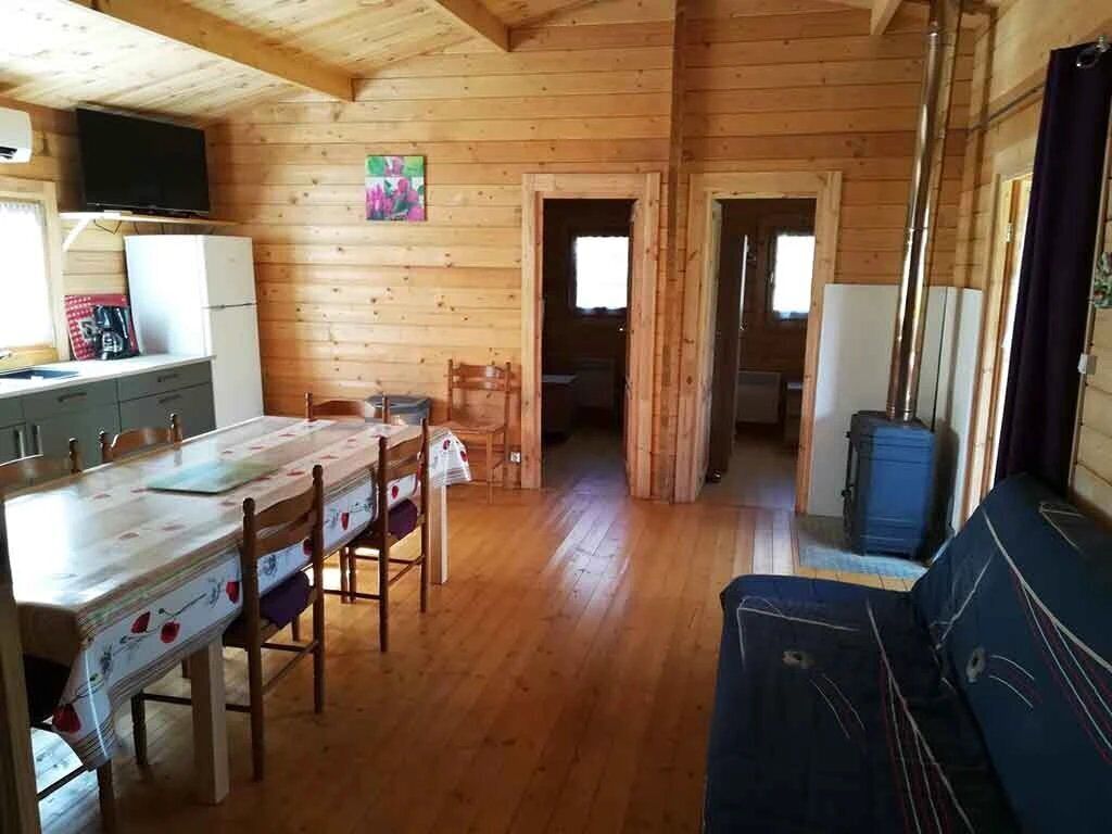 L’intérieur d’une cabane en bois comprend un coin repas, une cuisine et un espace de vie avec un canapé.