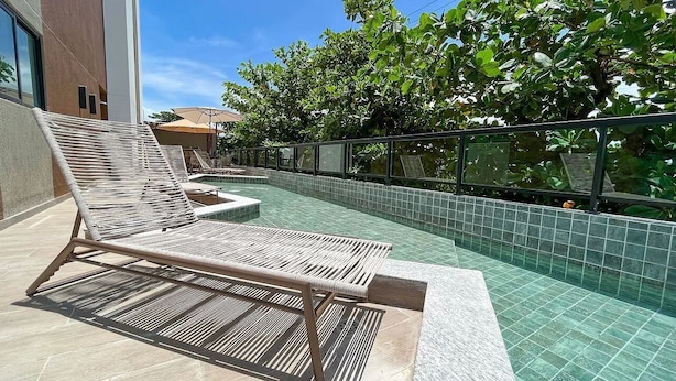 A pool area with lounge chairs and a tiled deck. - Villa Del Porto #307 - Flat in Porto by Carpediem (Ipojuca)