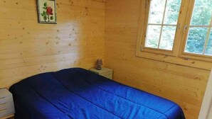 A room with a bed, a nightstand, a lamp, and a window with a view of trees.