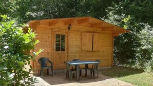 A wooden cabin with a deck and a table with chairs.