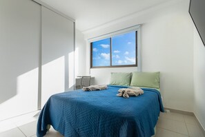 A bedroom with a large bed, a window with a view of the sky, and a chair. - Cupe Beach Living #102d - Triple by Carpediem (Ipojuca)