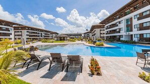 Um hotel moderno com piscina central, área de estar ao ar livre e um jardim bem cuidado.
