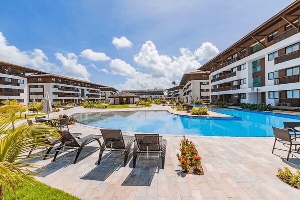 A modern hotel with a central swimming pool, outdoor seating, and a well-maintained garden area. - Cupe Beach Living #102d - Triple by Carpediem (Ipojuca)