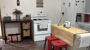 A compact kitchen with a white stove, a wooden countertop, and a red stool. - Pet-Friendly Home in Downtown Balaton (Balaton)