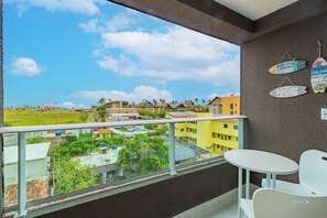 A balcony with a clear view of a residential area, a white table, and two chairs. - Suite #304 - Garden Coupe by Carpediem (Ipojuca)