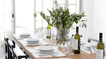 A dining table set with plates, glasses, and a vase of greenery.