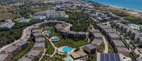 A resort with multiple swimming pools, a beach, and a view of the ocean.