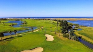 A golf course with water hazards, sand bunkers, and palm trees. - Salgados Resort Beach & Nature Escape (Albufeira)