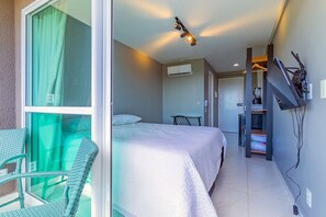 A hotel room with a bed, a chair, a TV mounted on the wall, and an air conditioning unit. - Cupe Garden #315 - Porto de Galinhas by Carpediem (Ipojuca)