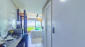 A modern kitchen with a large window, a built-in oven, and a sink. - Cupe Garden #315 - Porto de Galinhas by Carpediem (Ipojuca)