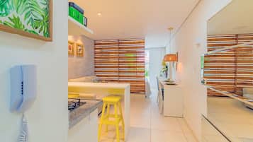 Una cocina moderna con un taburete amarillo, una encimera blanca y una estufa.