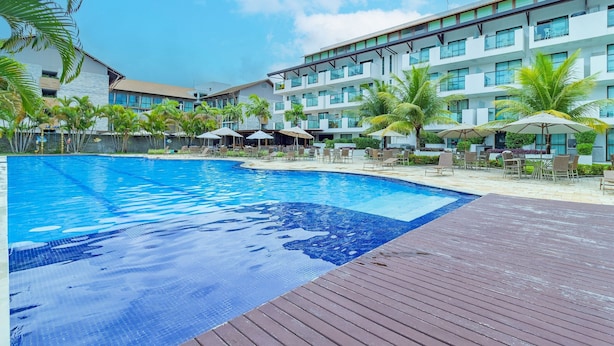 Un hotel con piscina, zona de estar al aire libre y palmeras.