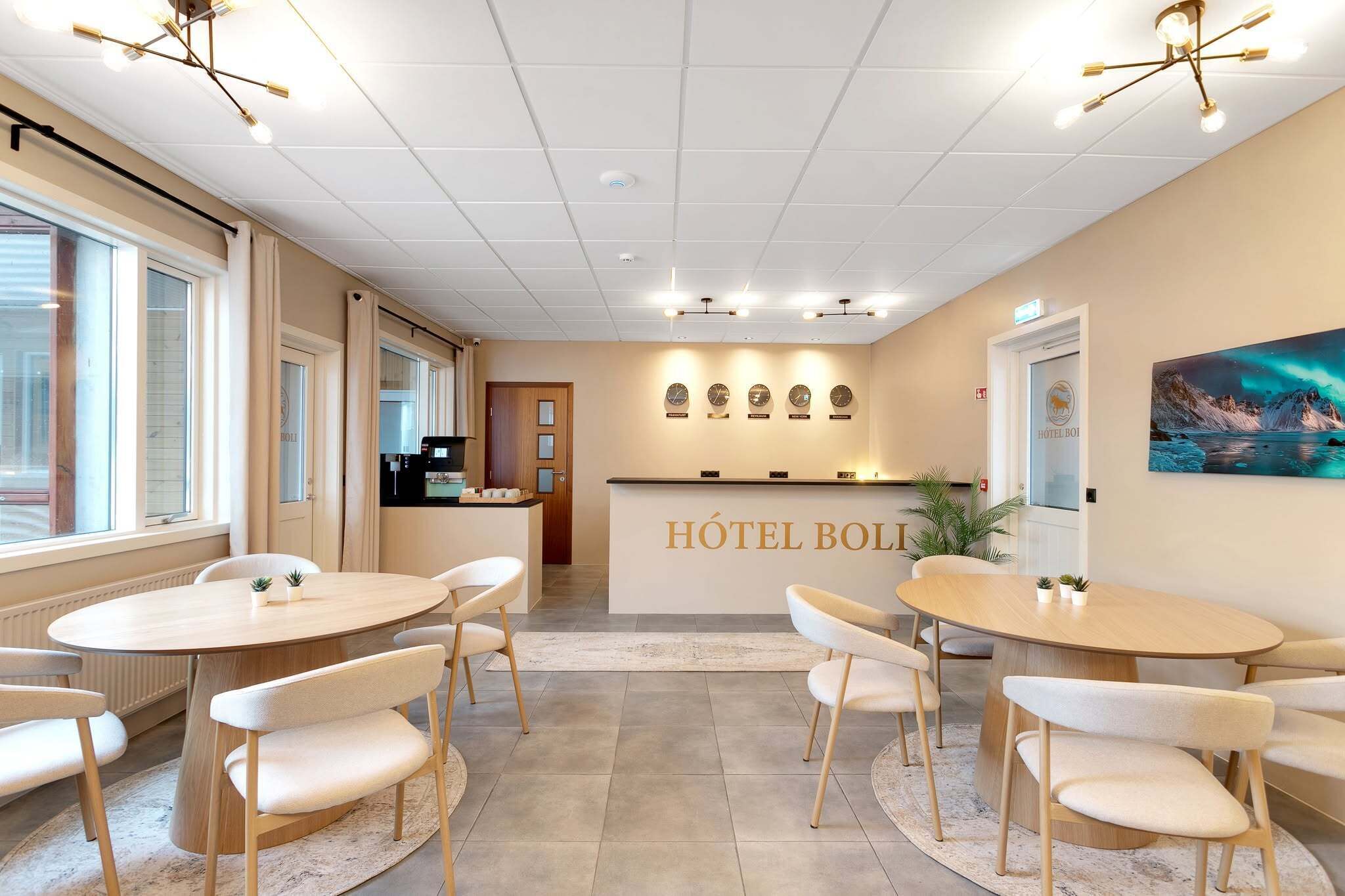 Un hall d’hôtel avec un comptoir d’accueil, une horloge et un tableau représentant des aurores boréales accroché au mur.