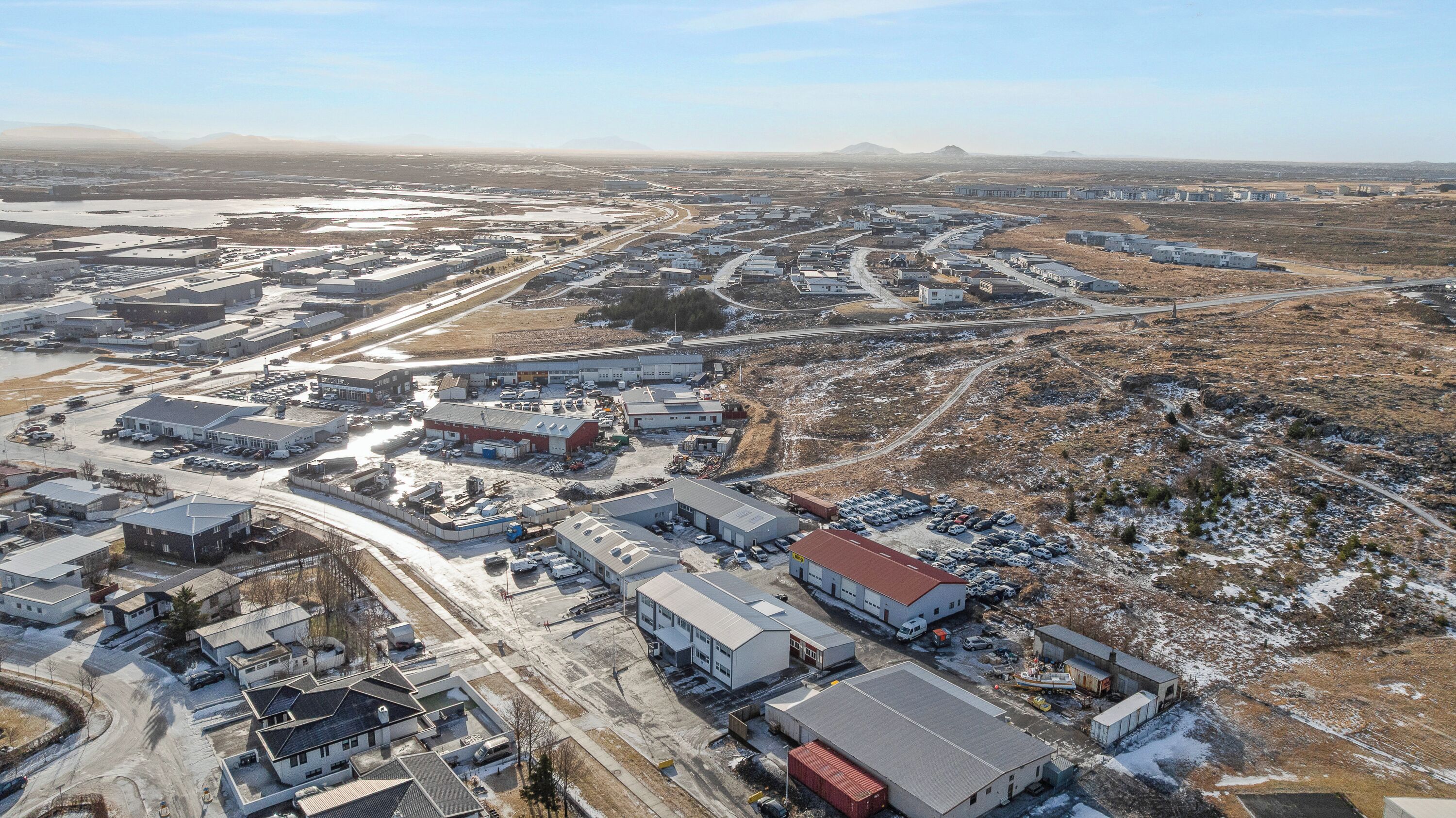 An industrial area with multiple buildings, roads, and parked vehicles.