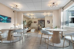 Un moderno vestíbulo de hotel con mesas y sillas redondas, una escalera y un ventanal grande.