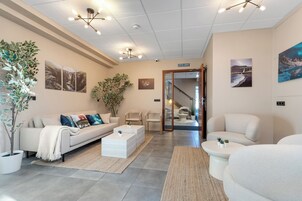 Una sala moderna con sofá, mesa de centro y sillas, una escalera que lleva a un piso superior y un cartel que indica la ubicación: Islandia.