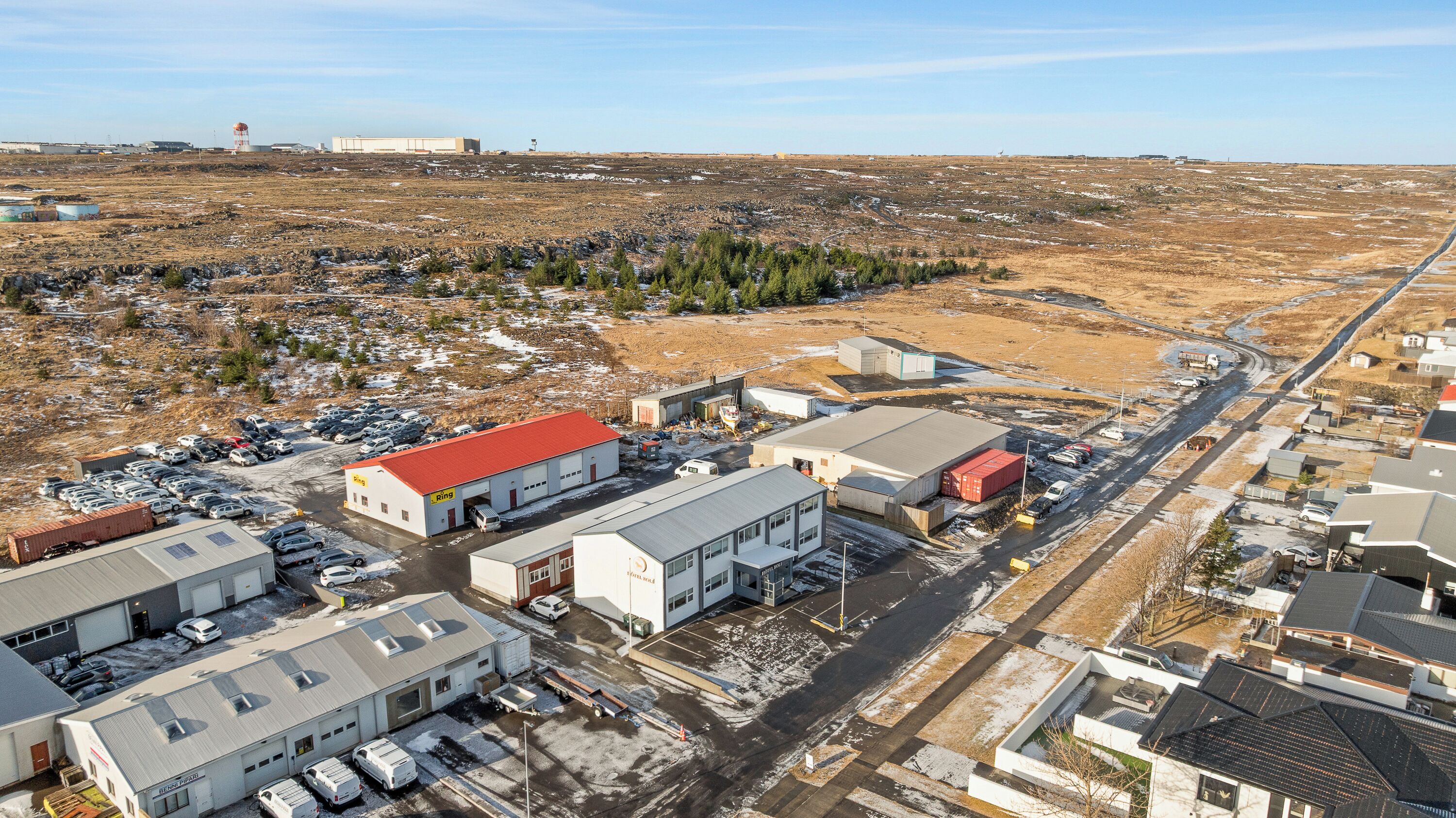 A commercial area with multiple buildings, parking lots, and a road.