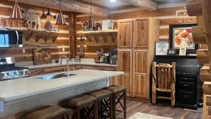 Una cocina rústica con vigas de madera, una isla central con taburetes y una mesa de comedor.
