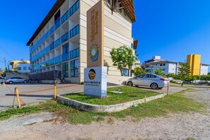 A building with a sign for "Patrimônio Inocorpeções" and a parking area with cars. - Manawa Beach #a33 - Porto de Galinhas By Carpediem (Ipojuca)