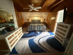 Ein Schlafzimmer mit einem Bett, einem Schminktisch, Nachttischen und einem Deckenventilator.