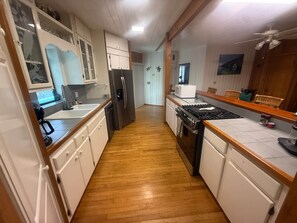 A kitchen with wooden flooring, white cabinets, a stainless steel refrigerator, a microwave, and a stove. - Peaceful Waterfront Tropical Paradise (Monroe County)