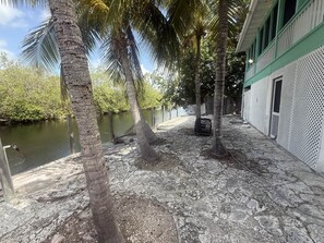 A courtyard with a water body, palm trees, and a building with a green and white facade. - Peaceful Waterfront Tropical Paradise (Monroe County)