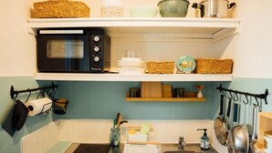 A kitchen with a microwave, shelves with dishes and baskets, a sink with a faucet, and hanging utensils. - Perfect 1-bedroom condo with AC in peaceful Saint-Paul-de-Vence (Saint-Paul-de-Vence)