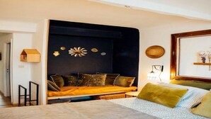 A bedroom with a bed, a sofa bed, and a wall-mounted shelf with decorative items. - Perfect 1-bedroom condo with AC in peaceful Saint-Paul-de-Vence (Saint-Paul-de-Vence)