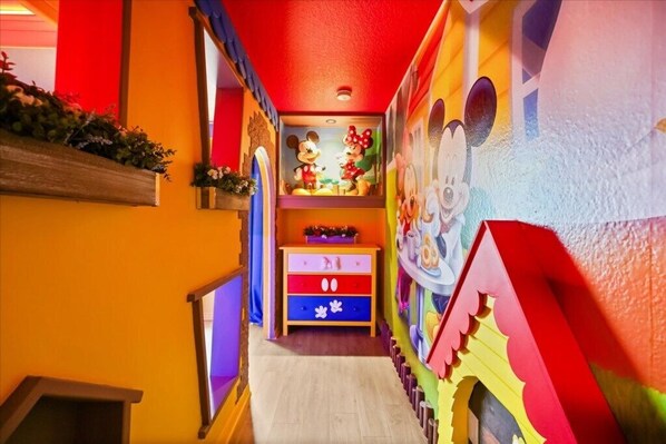 A brightly colored hallway with a Mickey Mouse mural, a wooden bench, and a colorful cabinet. - 4 BD/ 3 BA/ Storey Lake (4874 CT) (Kissimmee)