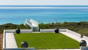 Una terrazza sul tetto con vista sull'oceano, una struttura bianca e tre grandi vasi.