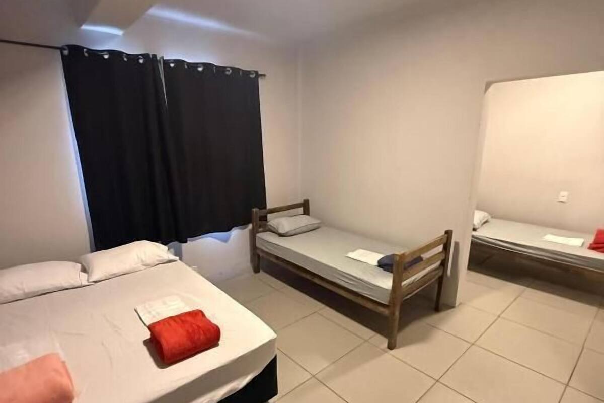 Une chambre avec deux lits, une fenêtre avec des rideaux et un luminaire au plafond.