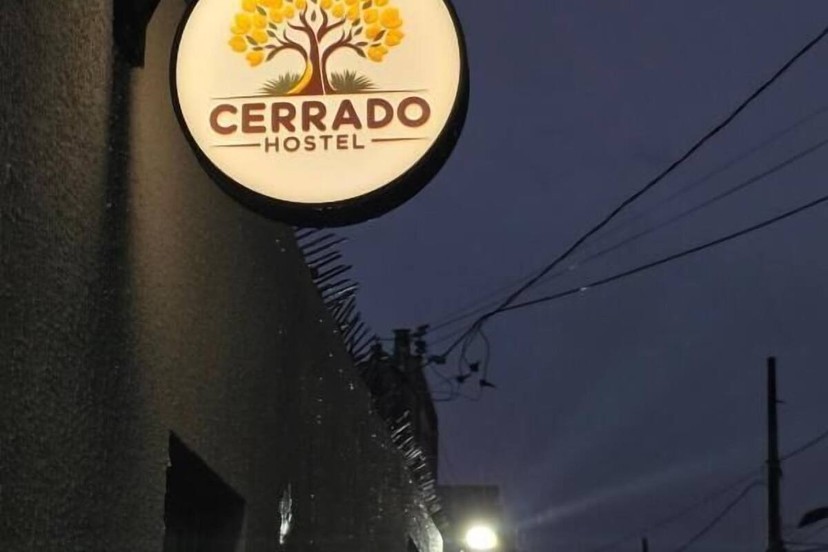 Une enseigne indiquant « Cerrado Hostel », avec un logo représentant un arbre et des fleurs jaunes.
